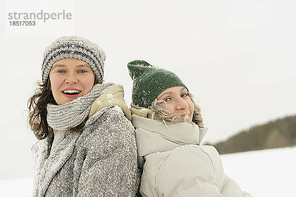 Fröhliche Freunde mit Strickmützen genießen den Schnee