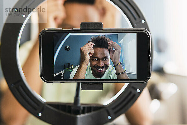 Smartphone-Bildschirm mit lächelndem Mann  der zu Hause ein Tutorial macht