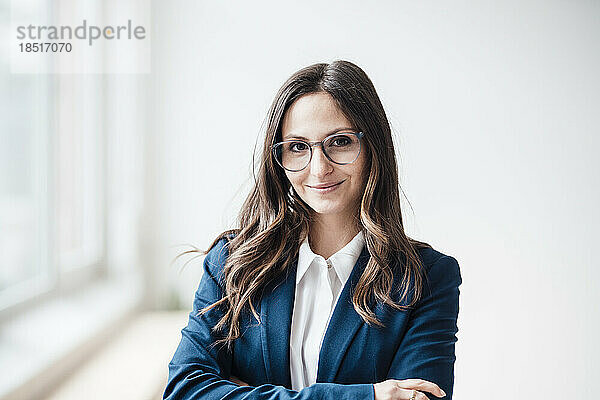 Lächelnde Geschäftsfrau mit Brille steht im Heimbüro