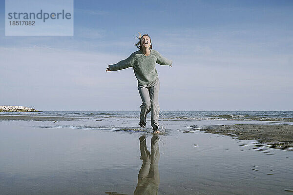 Glückliche Frau läuft am Ufer am Strand