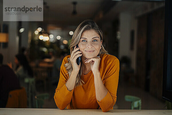 Lächelnde Frau nutzt ihr Smartphone im Café