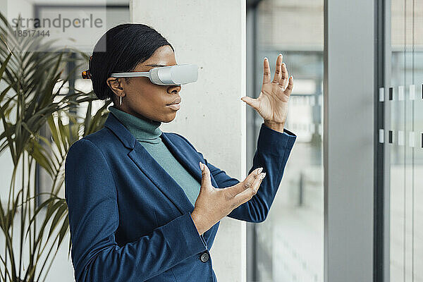 Geschäftsfrau mit Virtual-Reality-Headset gestikuliert im Büro