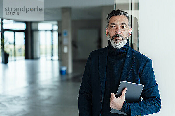 Geschäftsmann steht mit Tablet-Computer im Büro