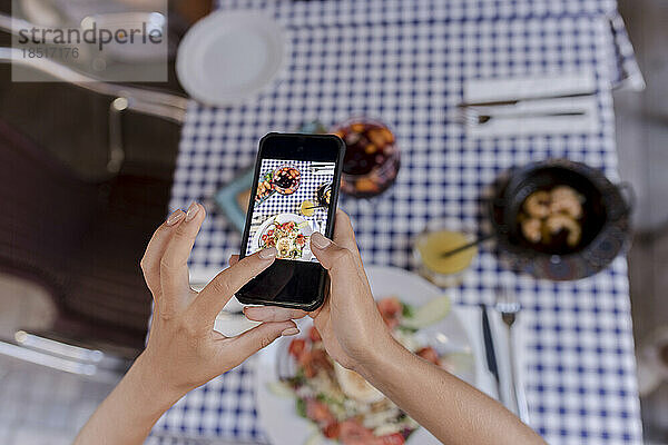Frau fotografiert Essen mit Smartphone