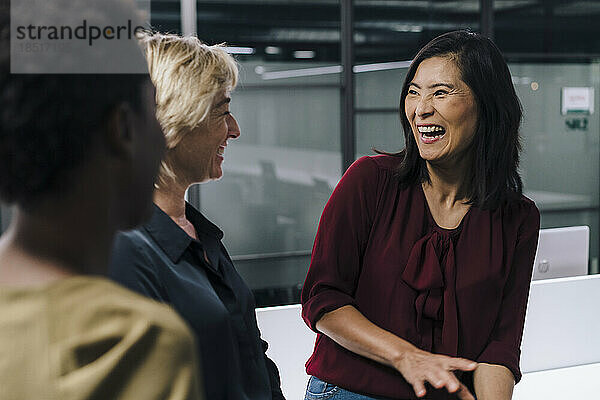 Geschäftsfrauen lachen mit Kollegen im Büro