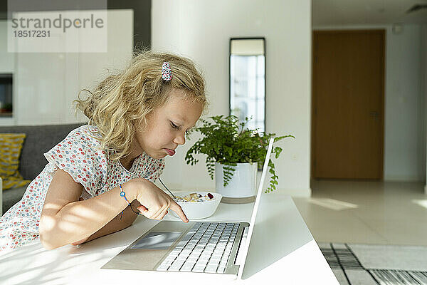 Blondes Mädchen tippt zu Hause am Laptop