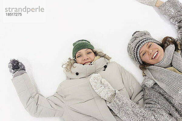 Fröhliche Freunde  die sich hinlegen und den Schnee genießen