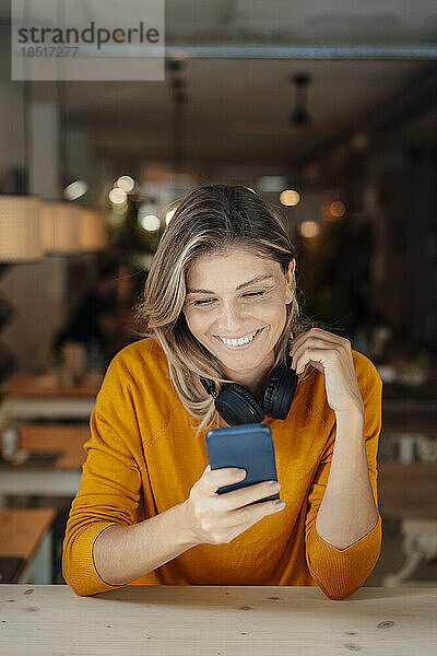 Glückliche Frau surft im Café mit Smartphone im Internet