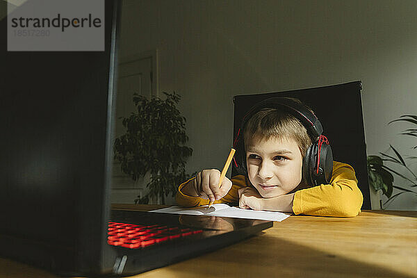 Junge mit Headset lernt zu Hause online über Laptop