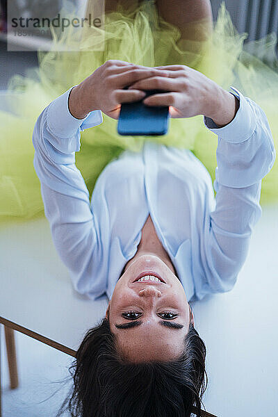 Happy businesswoman lying on desk with smart phone