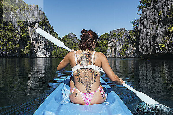 Frau mit Tätowierung auf dem Rücken beim Kajakfahren auf See