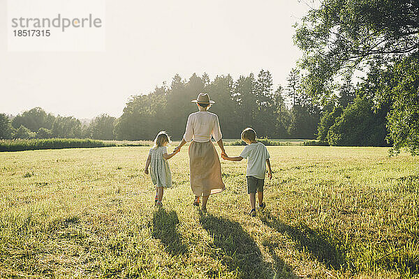 Glückliche Mutter geht mit Sohn und Tochter an einem sonnigen Tag spazieren