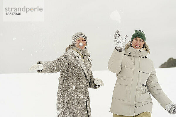 Glückliche Frauen genießen es  im Winter Schneeball zu werfen