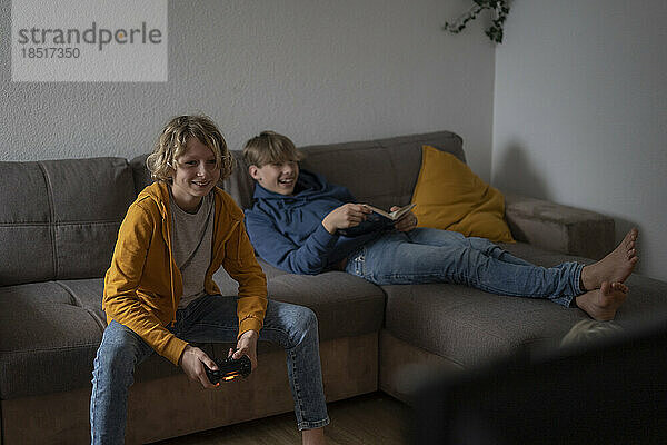 Happy boy playing video game with friend at home