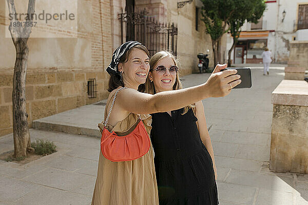 Fröhliche Freunde  die an einem sonnigen Tag ein Selfie mit dem Smartphone machen