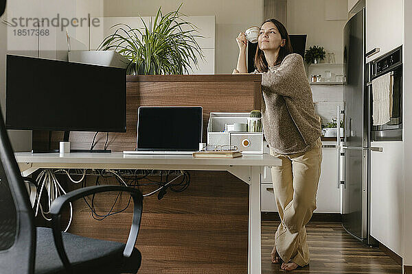 Nachdenklicher Freiberufler mit Kaffeetasse im Heimbüro