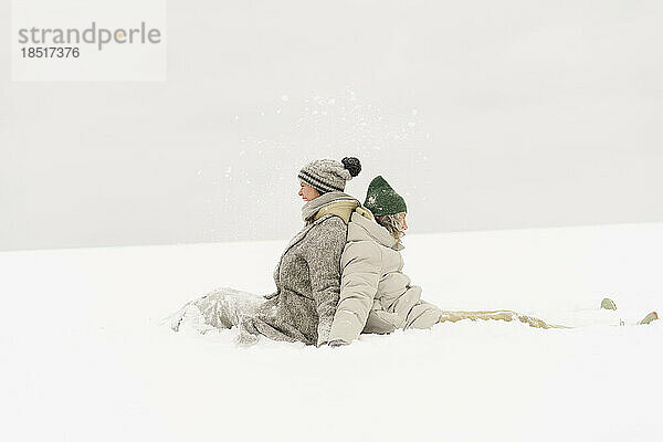 Freunde genießen es  Rücken an Rücken im Schnee zu sitzen