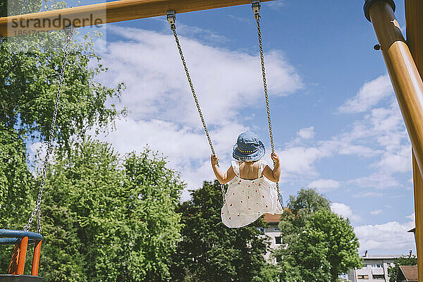 Mädchen mit Hut schwingt auf Schaukel im Park
