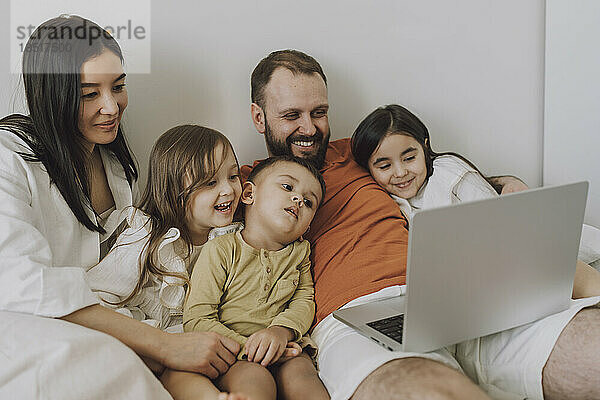 Lächelnde Familie  die zu Hause gemeinsam einen Laptop benutzt