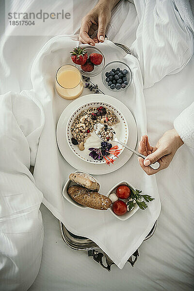 Frau frühstückt zu Hause im Bett