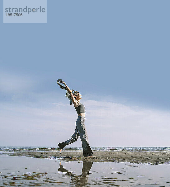 Spiegelbild einer Frau  die am Strand vor dem Himmel genießt