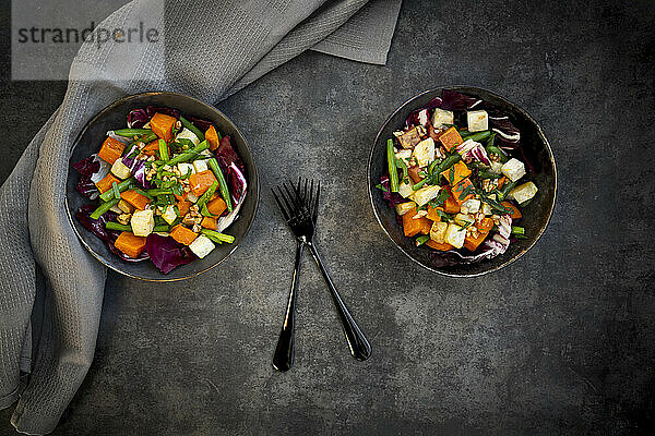 Zwei Schüsseln verzehrfertiger vegetarischer Salat mit Süßkartoffeln  Sellerie  Radicchio  grünen Bohnen  Croutons  Walnüssen und Petersilie