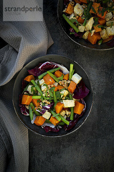 Zwei Schüsseln verzehrfertiger vegetarischer Salat mit Süßkartoffeln  Sellerie  Radicchio  grünen Bohnen  Croutons  Walnüssen und Petersilie