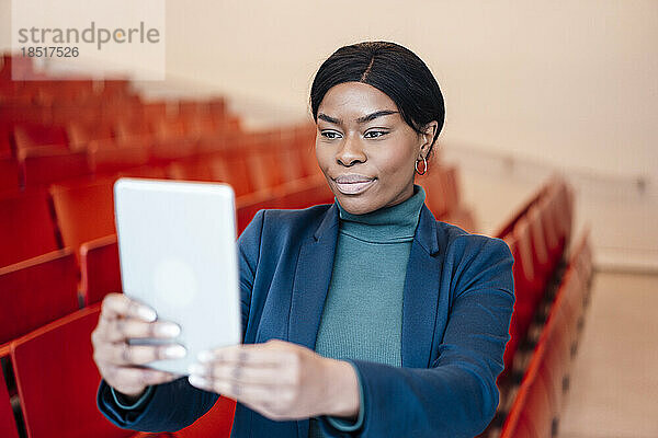 Junge Frau macht Selfie mit Tablet-PC im Zuschauerraum