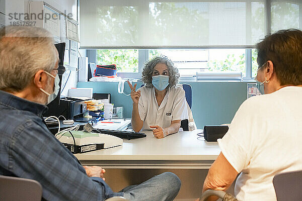 Arzt diskutiert mit älteren Patienten  die in der Klinik sitzen