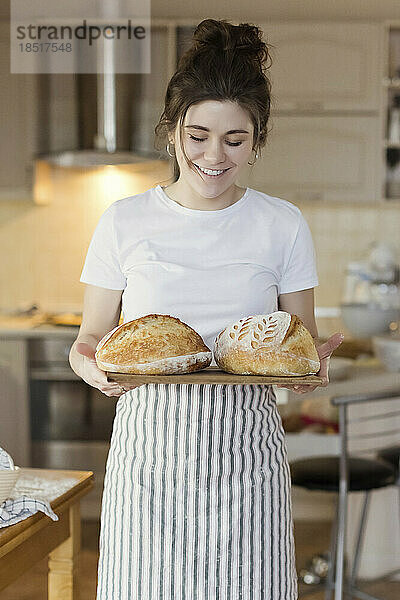 Glückliche Frau hält frisch gebackene Brote