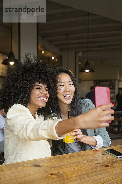 Glückliche Frau macht Selfie mit Freund im Café