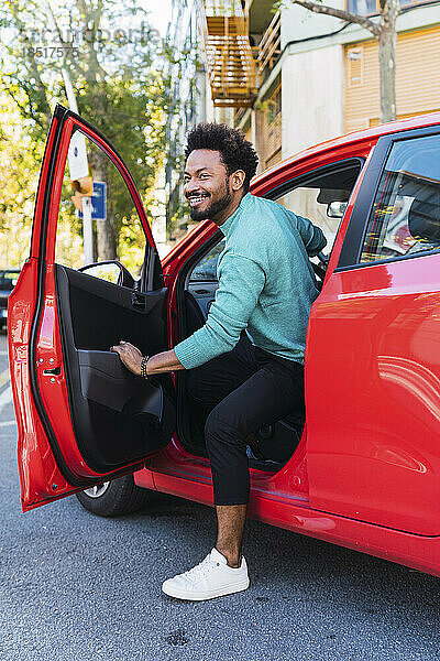 Lächelnder Mann steigt aus rotem Auto