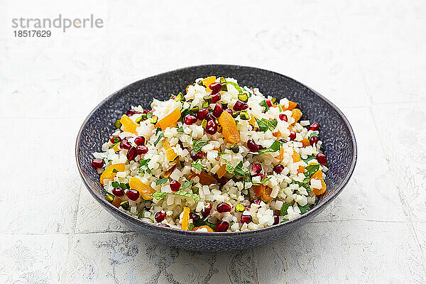 Bowl of cauliflower salad with pomegranate seeds  pistachios  mint  parsley and dried apricot