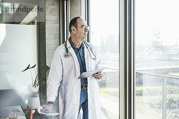 Nachdenklicher Arzt  der durch das Fenster schaut