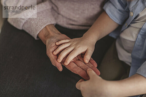 Enkel berührt die Hand einer älteren Frau zu Hause