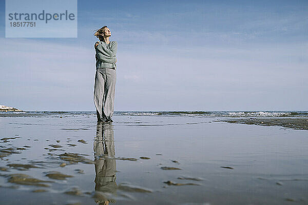 Frau umarmt sich am Strand