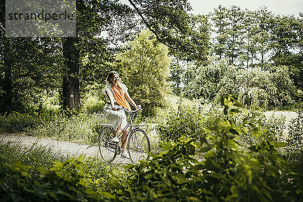 Frau fährt Fahrrad inmitten von Bäumen