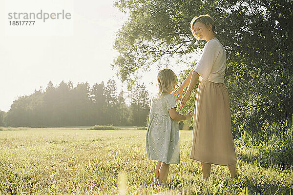 Mutter und Tochter stehen an einem sonnigen Tag in der Natur