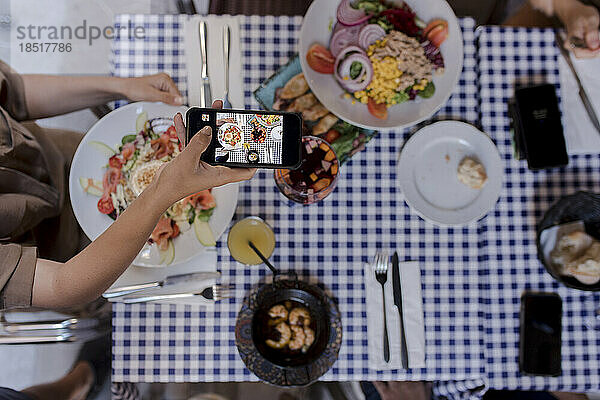 Junge Frau fotografiert Essen per Smartphone