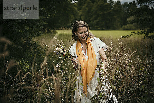 Lächelnde Frau hält Wildblumen im Feld