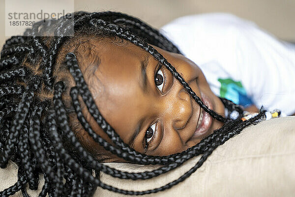 Smiling girl with braided hair lying at home