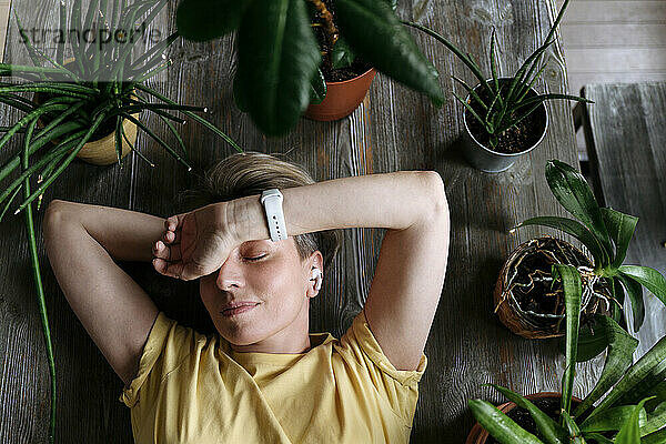 Reife Frau schläft zu Hause inmitten von Pflanzen