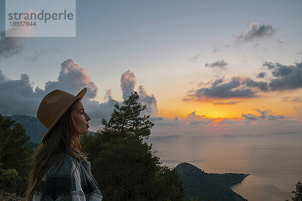 Frau mit Hut genießt den Sonnenuntergang im Urlaub