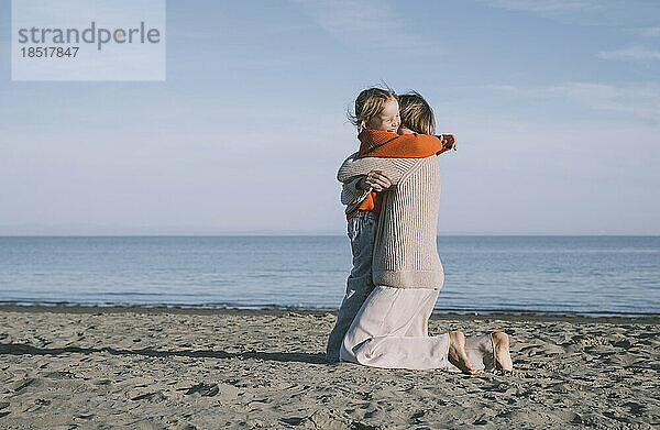 Fröhliche Tochter umarmt Mutter am Strand