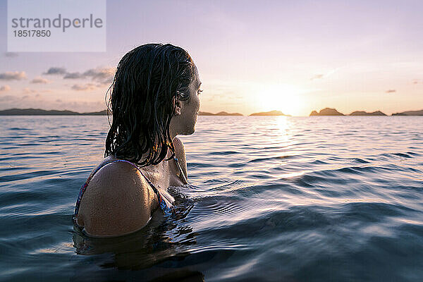 Woman swimming in sea looking at sun