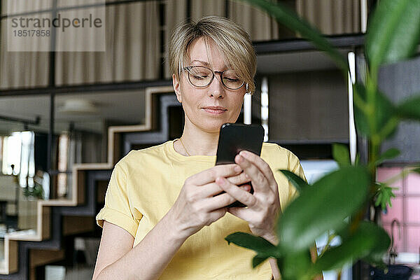 Frau mit Brille und Smartphone zu Hause