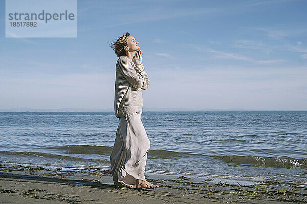 Frau läuft am Ufer des Strandes vor dem Himmel