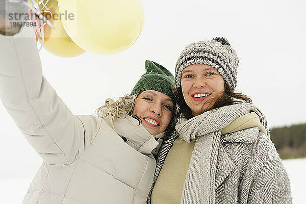 Glückliche Frauen mit Strickmützen genießen den Winter