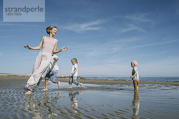 Fröhliche Mutter spielt mit Kindern am Strand