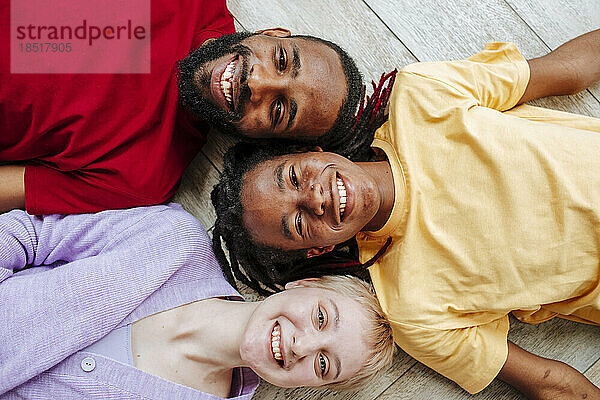 Happy young woman with friends lying on floor at home